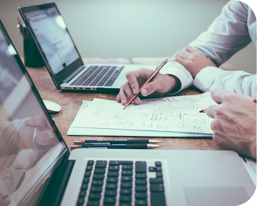 Traders collaborating on a trading plan with laptops and notes