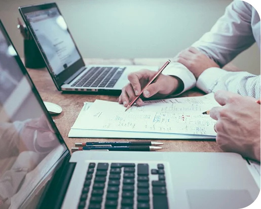 Traders collaborating on a trading plan with laptops and notes